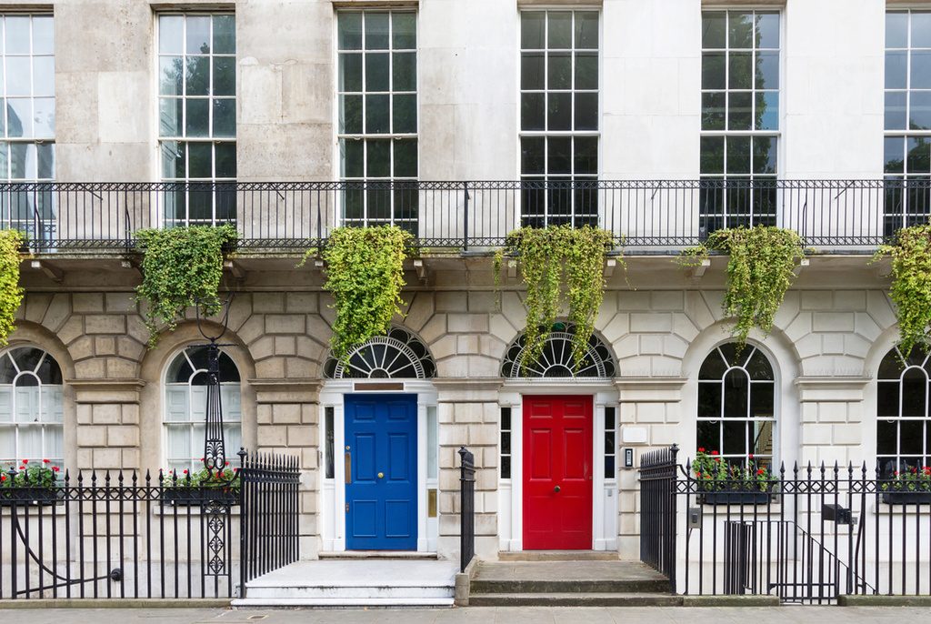 Georgian-inspired house with two adjacent front doors coloured blue (left) and red (right) with sash windows